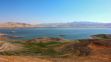 Sakin tepeler ve uzak dağlarla birlikte nefes kesici bir göl araziye yayılır..