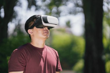 Young man using VR virtual reality headset with nature background for connect future digital technology metaverse entertainment 