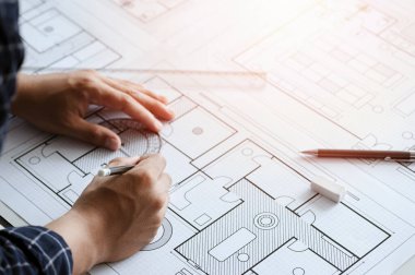 Close up of engineer drawing on blueprint architectural project at a desk in the office. inspection workplace for architectural plan, sketching a construction project. Construction concept