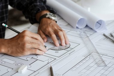 Close up of engineer drawing on blueprint architectural project at a desk in the office. inspection workplace for architectural plan, sketching a construction project. Construction concept