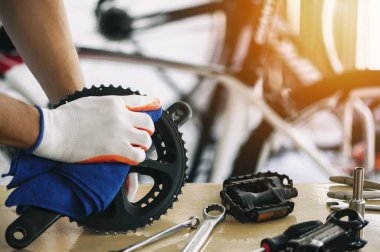 close - up of the male mechanic working in the bicycle repair shop, mechanic repairing bike using a special tool, wearing protective gloves. Bike Maintenance Concept.