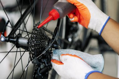 close - up of the male mechanic working in the bicycle repair shop, mechanic repairing bike using a special tool, wearing protective gloves. Bike Maintenance Concept.
