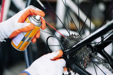 close - up of the male mechanic working in the bicycle repair shop, mechanic repairing bike using a special tool, wearing protective gloves. Bike Maintenance Concept.
