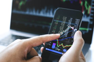 Businessman hand holding phone and analysis finance market graph stock market trading,stock chart and investment concept.