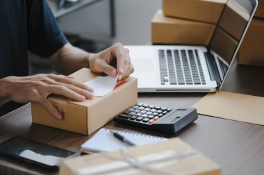 Young man entrepreneur small business SME Freelance receive order client and working with packaging sort box delivery online market on purchase order and preparing package product parcel for shipment