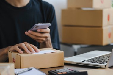 Young man entrepreneur small business SME Freelance receive order client and working with packaging sort box delivery online market on purchase order and preparing package product parcel for shipment