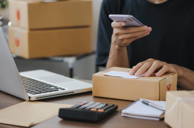 Young man entrepreneur small business SME Freelance receive order client and working with packaging sort box delivery online market on purchase order and preparing package product parcel for shipment