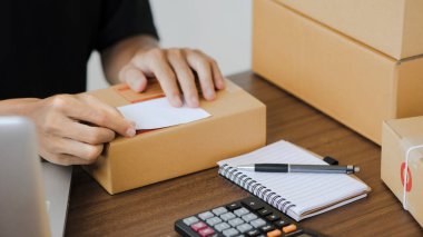 Young man entrepreneur small business SME Freelance receive order client and working with packaging sort box delivery online market on purchase order and preparing package product parcel for shipment