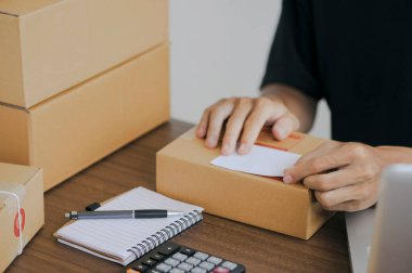 Young man entrepreneur small business SME Freelance receive order client and working with packaging sort box delivery online market on purchase order and preparing package product parcel for shipment