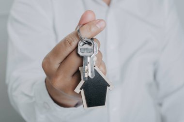 Men hand holding house key, real estate agent. Mortgage concept. Real estate, Buy sell, moving home, or renting property.