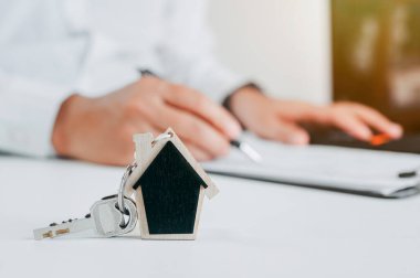 a house key and house model with the real estate agent and customer discussing for the contract to buy house, insurance, or loan real estate background. 