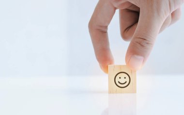 Close up of hand customer hand choose a smiley face icon on the wood cube, Service rating, satisfaction concept. best excellent business services rating customer experience.