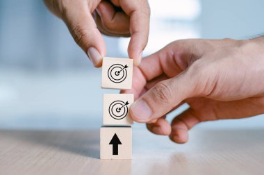 Business Hand putting virtual target board and arrow which print screen on the wooden cube. Business achievement goal and objective target concept.  