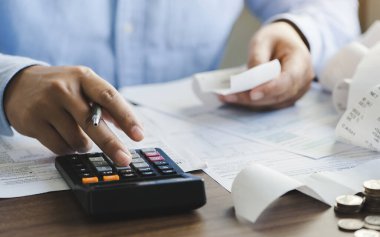 young man holding pen working on calculator to calculate business data, taxes, bills payment, Start up counting finance.accounting, statistics, and analytic research concept
