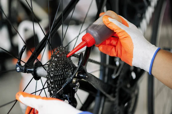 close - up of the male mechanic working in the bicycle repair shop, mechanic repairing bike using a special tool, wearing protective gloves. Bike Maintenance Concept.