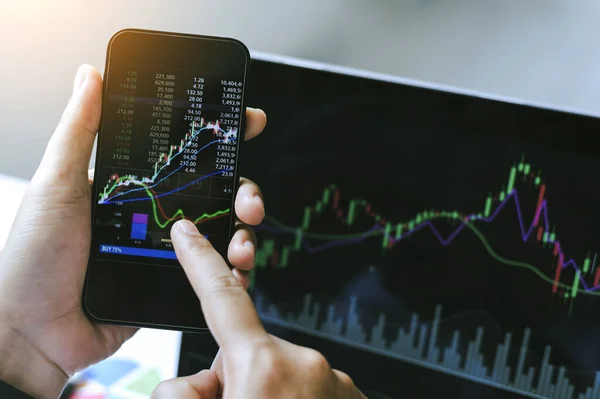 Businessman hand holding phone and analysis finance market graph stock market trading,stock chart and investment concept.