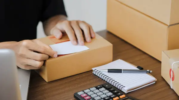 Young man entrepreneur small business SME Freelance receive order client and working with packaging sort box delivery online market on purchase order and preparing package product parcel for shipment