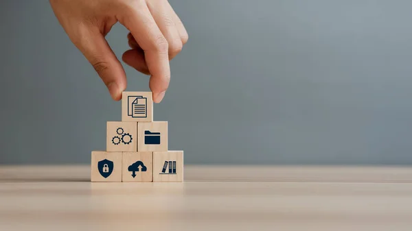 Hand putting document icon in the wooden cube for document management digital file data online records keeping, database technology, file access, and doc sharing.