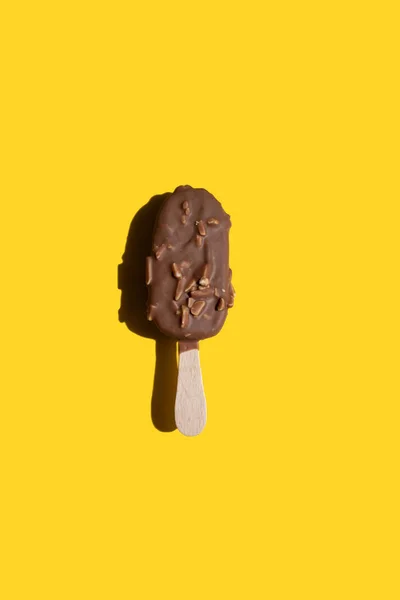 stock image ice cream on a stick in white chocolate with cookies and in milk chocolate with nuts on a yellow background