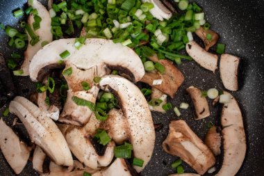 Mantarlar (kraliyet şampiyonları) ve yeşil soğanlar baharatlı bir tavada kızartılır.