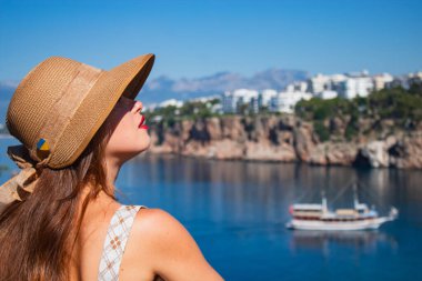 Şapkalı genç bir kız geminin ve denizin gözlem güvertesine bakıyor.