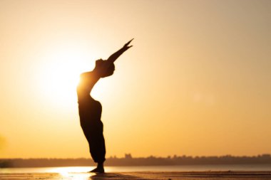 Şafakta yoga yapan bir kızın bulanık silüeti.