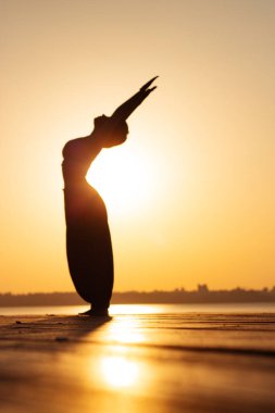 Şafakta yoga yapan bir kızın bulanık silüeti.