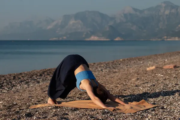 stock image the girl on the background of the sea is doing classical yoga