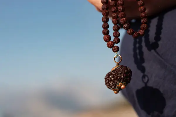 stock image a girl on the background of the sea is holding a rudraksha necklace