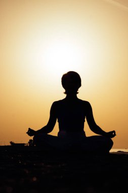 Gün batımında yoga ya da pilates yapan genç bir kadın silueti ya da güzel bir dağ yerinde güneşin doğuşu. Beden ve zihin rahatlığı için fiziksel aktivite, sağlıklı yaşam tarzı alışkanlıkları kavramı 