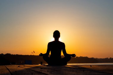Açık hava takibi. sağlıklı yaşam tarzı konsepti. Yoga yapan bir kadının günbatımı silueti.