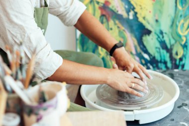 Seramik dersi, çömlekçinin tekerinde kil tabak yapan bir adam.