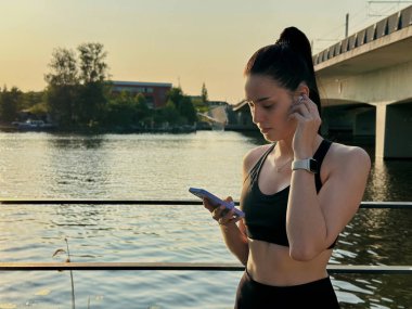 Genç bir atlet bacak esnetme egzersizi yapıyor. Siyah takım elbise giyiyor. Başka yere bak.