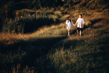 Gün batımında el ele tutuşan genç bir çift.