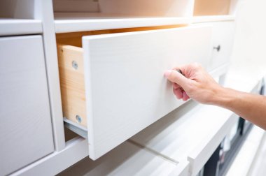 Erkek el çekme ve beyaz ahşap dolaptaki çekmeceyi açma. Ev eşyaları ve dekorasyon alışveriş konsepti