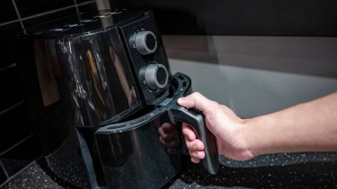 Erkek el mutfakta elektrikli bir tava tutacağı tutuyor. Sağlıklı pişirme yaşam tarzı için ev aletleri.