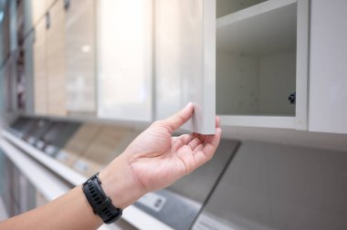 Erkek el mobilya mağazasında beyaz dolap kapağını açıyor. Ev geliştirme kavramı