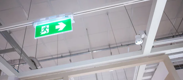 Green emergency exit sign or fire exit sign showing the way to escape with arrow symbol.