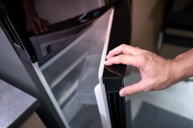 Erkek eli buzdolabı açıyor ya da mutfak galerisinde buzdolabı kapısı var. Ev iç tasarımı için aygıt satın alınıyor.