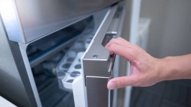 Erkek eli buzdolabı açıyor ya da mutfak galerisinde buzdolabı kapısı var. Ev iç tasarımı için aygıt satın alınıyor.