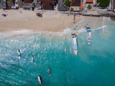 Nusa Lembongan 'daki Jungutbatu sahilinin kıyı şeridi manzarası turist hız teknesiyle demirli. Endonezya 'daki Bali adasına yakın bir tatil beldesi..