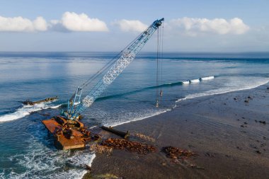 Bali, Endonezya 'ya yakın bir ada olan Nusa Lembongan plajı yakınlarında terk edilmiş bir vinç manzarası..