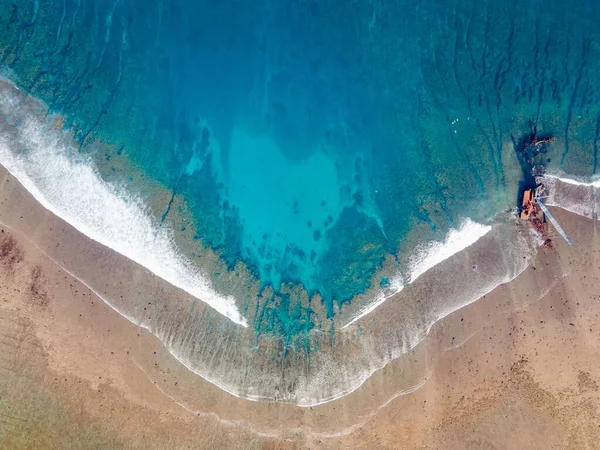 Endonezya 'nın Bali adası yakınlarındaki Nusa Lembongan' da terk edilmiş bir vinçle tropikal plaj manzarasına ulaşan deniz dalgalarının hava görüntüsü..