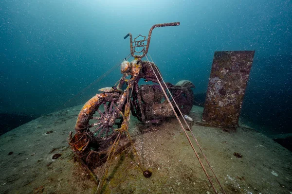Underwater scene of submerged rusty motorcycle for artificial coral reef at Tor 13 dive site or the underwater museum in Andaman sea, Thailand.