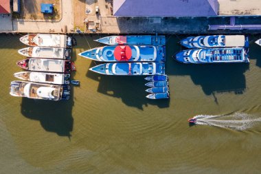 Yat limanına demirlemiş tur teknelerinin havadan görüntüsü ve botun hızı yakınlarda. Phuket, Tayland rıhtımındaki motorlu teknelerin insansız hava aracı görüntüsü. Deniz taşımacılığı işi ve deniz turizmi