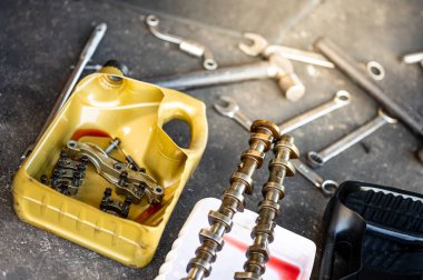 Garaj atölyesindeki beton zeminde İngiliz anahtarı ve çekiç gibi mekanik aletlerle galon olarak ikiye bölünmüş otomobil parçaları.