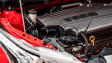 Araba tamirhanesinde kırmızı arabanın kaputunun altında yeni modern araba motoru. Makine mühendisliği ve otomotiv endüstrisi kavramları
