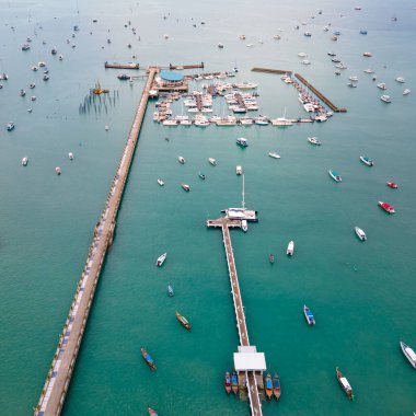 Phuket, Tayland 'daki Chalong İskelesi' nin insansız hava aracı görüntüsü. Birçok tekne, yat ve sürat teknesi iskeleye demirlemiş ve Andaman Denizi 'ni dolaşmaya başlamak için Ao Chalong Körfezi' ne demirlemiş..