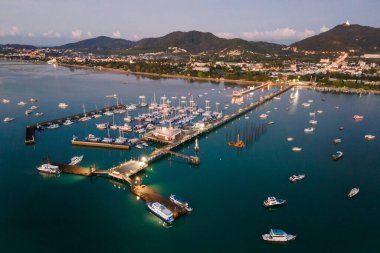 Şafakta Phuket, Tayland 'da Chalong İskelesi' nin aydınlanmış insansız hava aracı görüntüsü. Andaman Denizi 'nin etrafındaki merkezlerden biri olan Ao Chalong Körfezi rıhtımına demirlemiş pek çok tekne, yat ve sürat teknesi var.