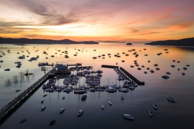 Phuket, Tayland 'da güneş doğarken Chalong İskelesi' nin insansız hava aracı görüntüsü. Birçok yat, katamaran ve sürat tekneleri Andaman Denizi 'nin etrafındaki merkezlerden biri olan Ao Chalong Körfezi rıhtımına demirlemişti..